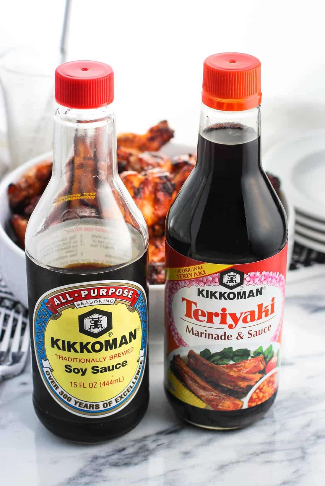 A bottle of Kikkoman soy sauce (left) and Teriyaki sauce (right) in front of the wings.