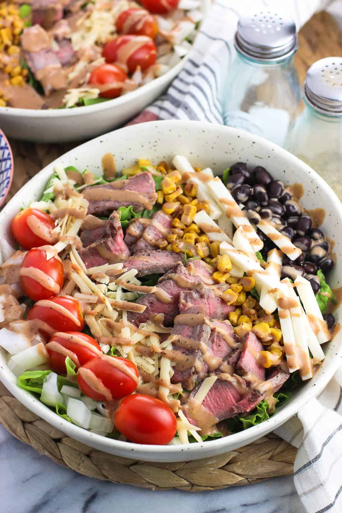 A steak salad with toppings arranged in neat lines on top.