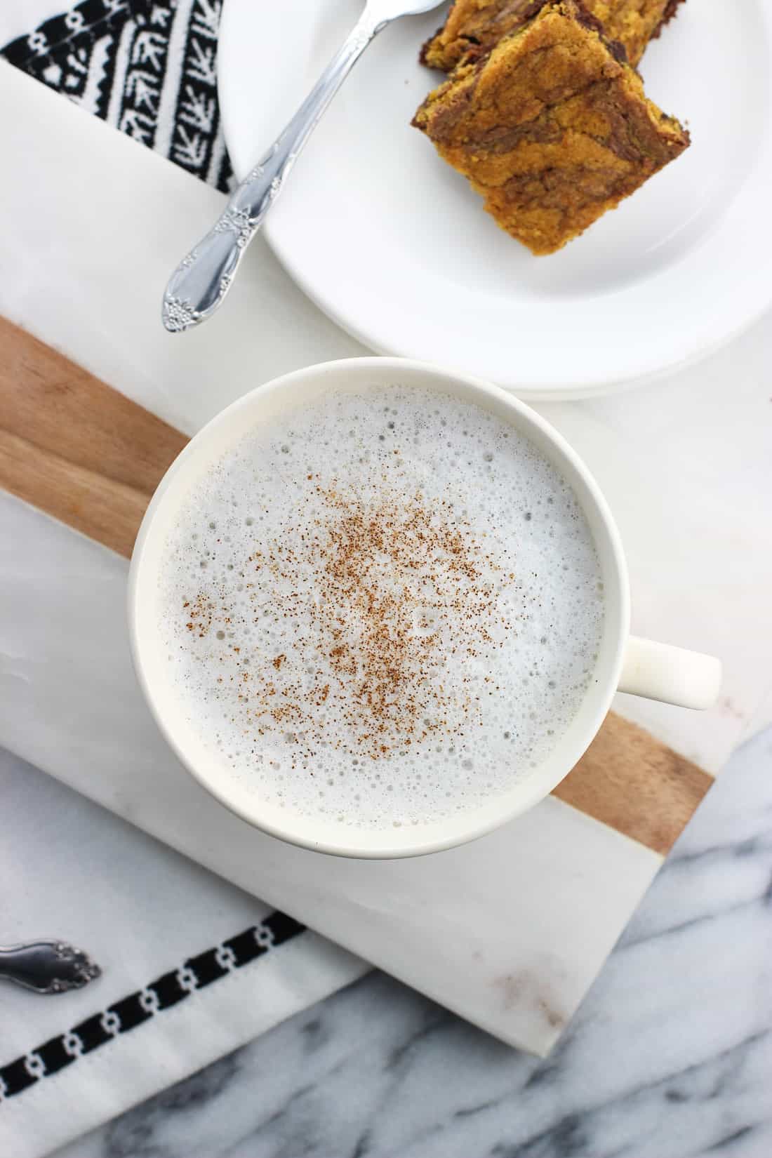 Eine Tasse Kamillenlatte neben einem Dessertteller Brownies.