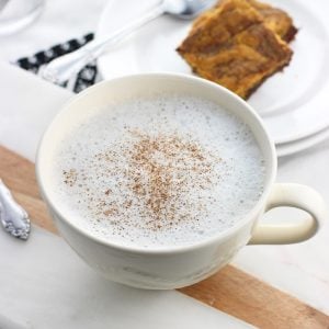 Un latte de thé à la camomille dans une grande tasse avec de la cannelle saupoudrée sur le dessus.