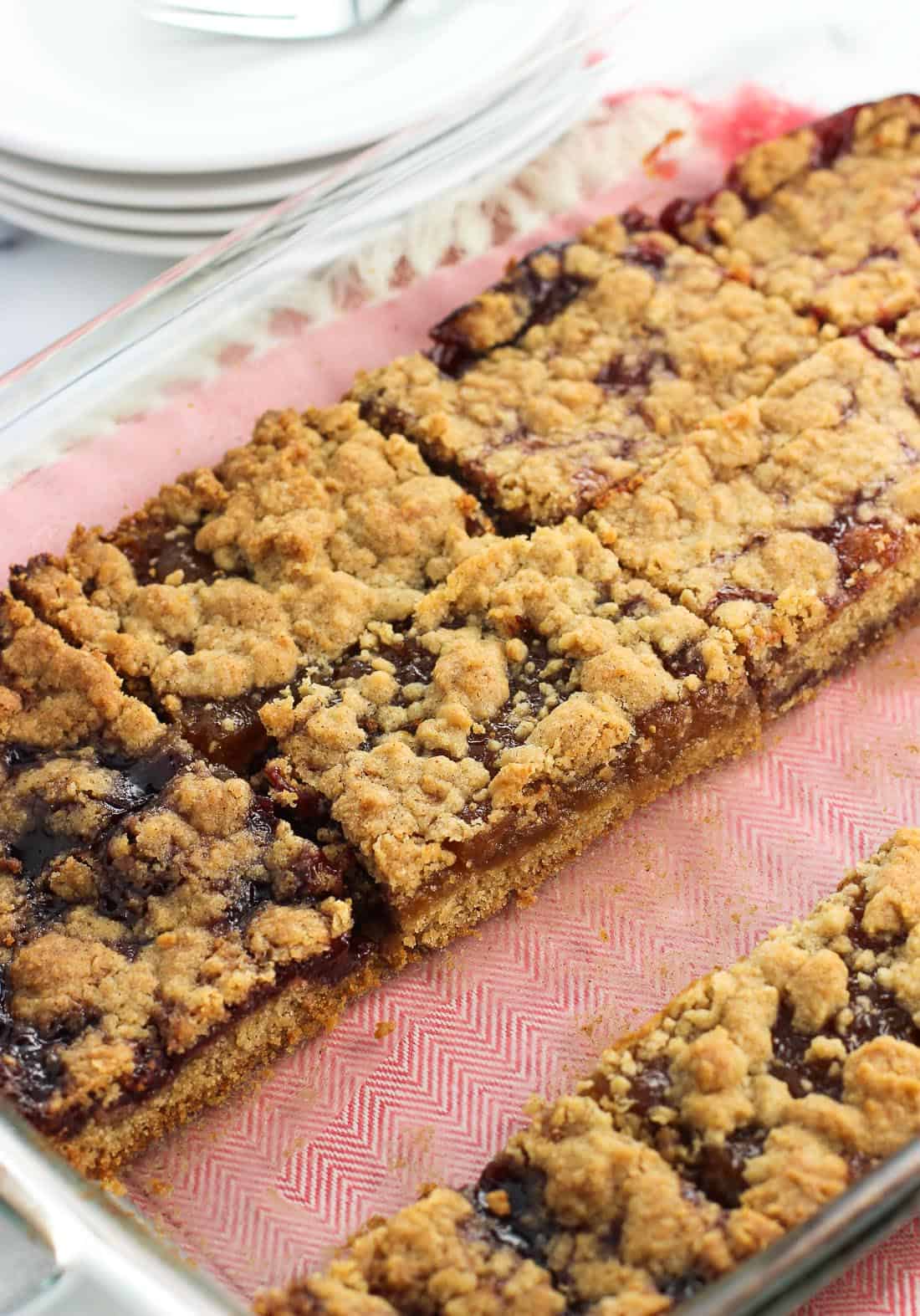 A strip of sliced jam bars removed from the baking dish so you can see the layers of the bars remaining