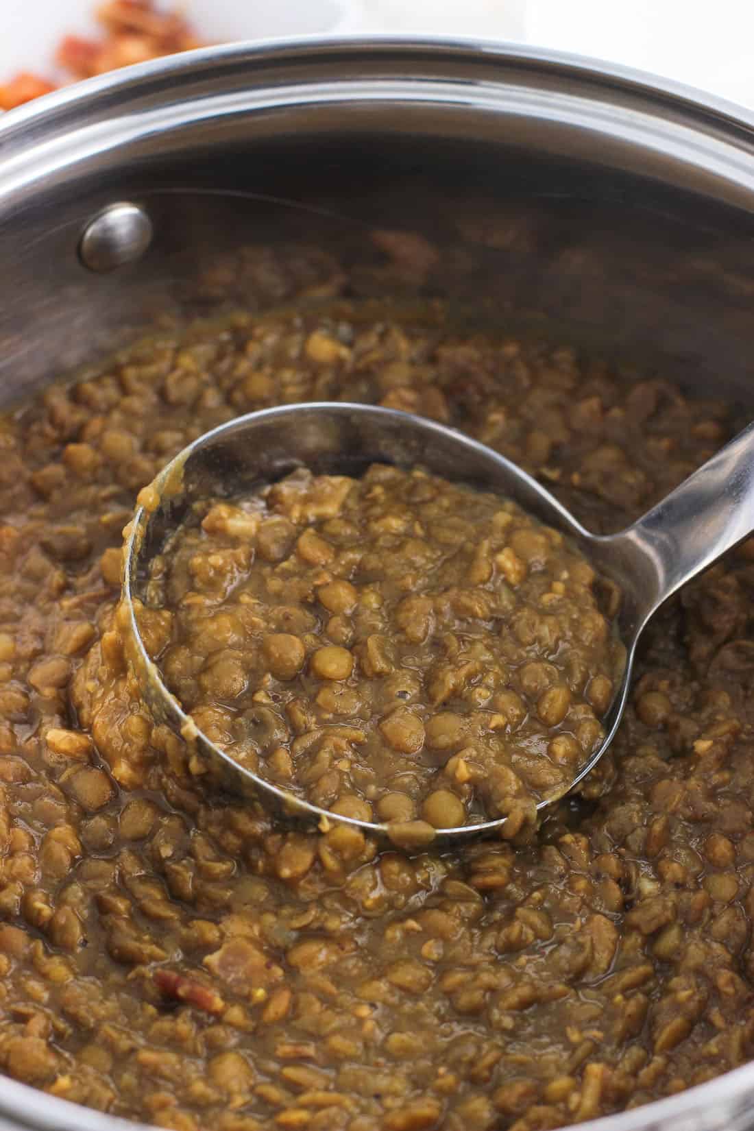 A ladle lifting out lentil soup from the pot.