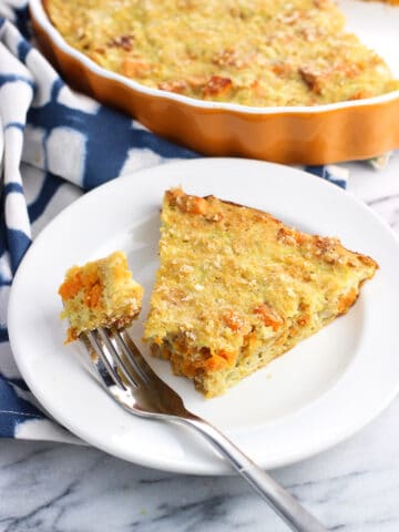 A slice of zucchini pie on a plate with a piece speared on a fork.
