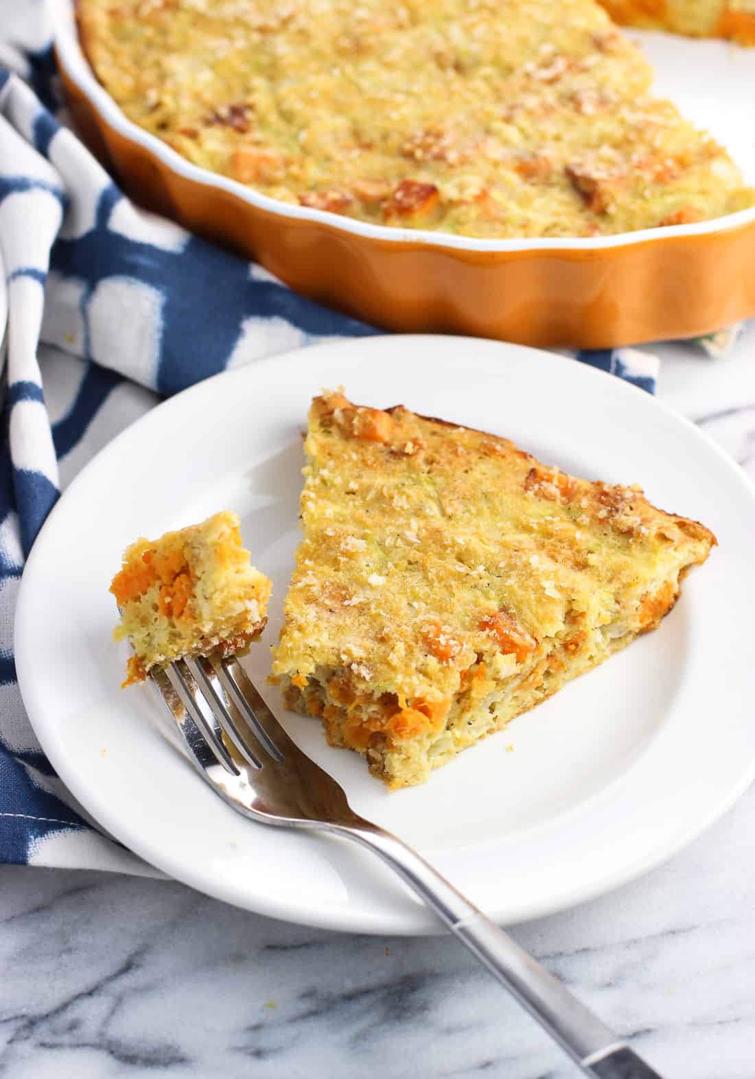 A slice of zucchini pie on a plate with a piece speared on a fork.