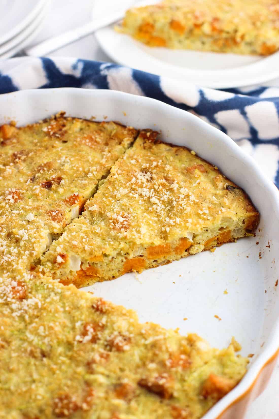 Sliced zucchini pie in a fluted ceramic tart pan.