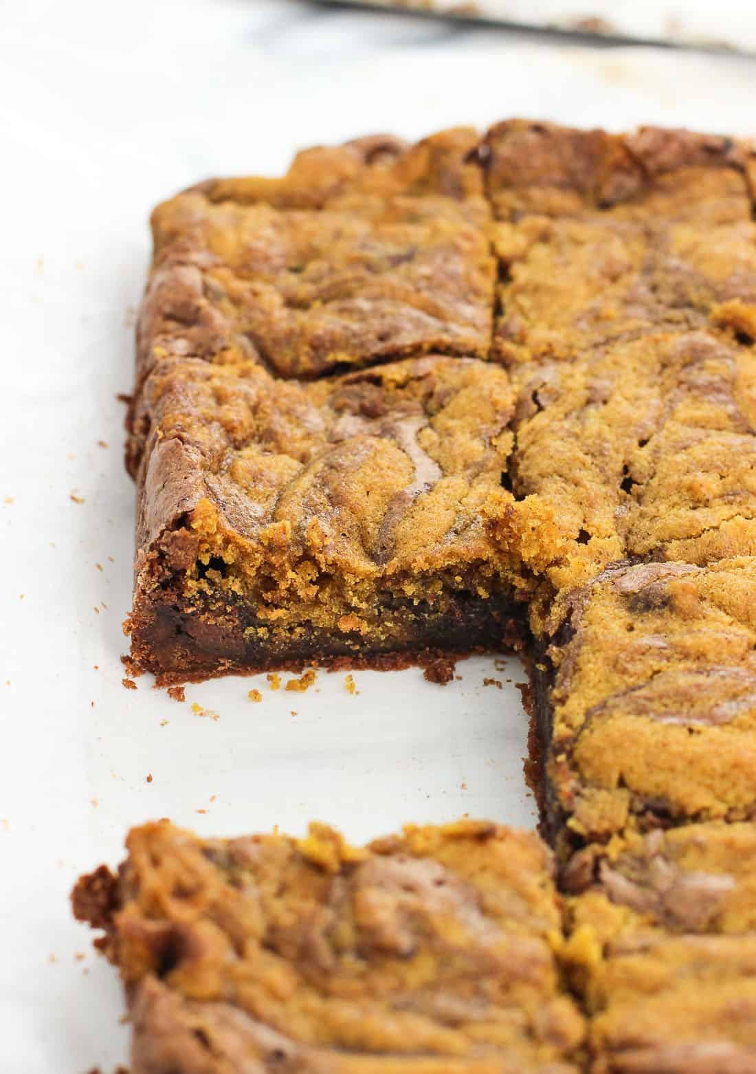 A side profile view of a slab of brownies with one removed.