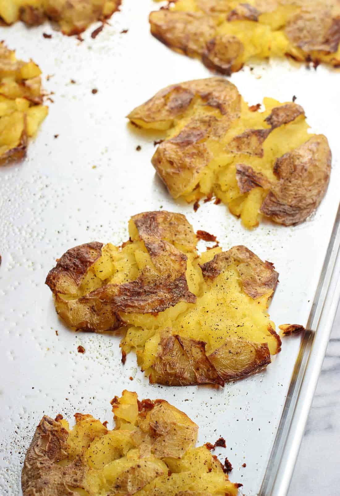 Crisped smashed potatoes on a greased metal baking sheet