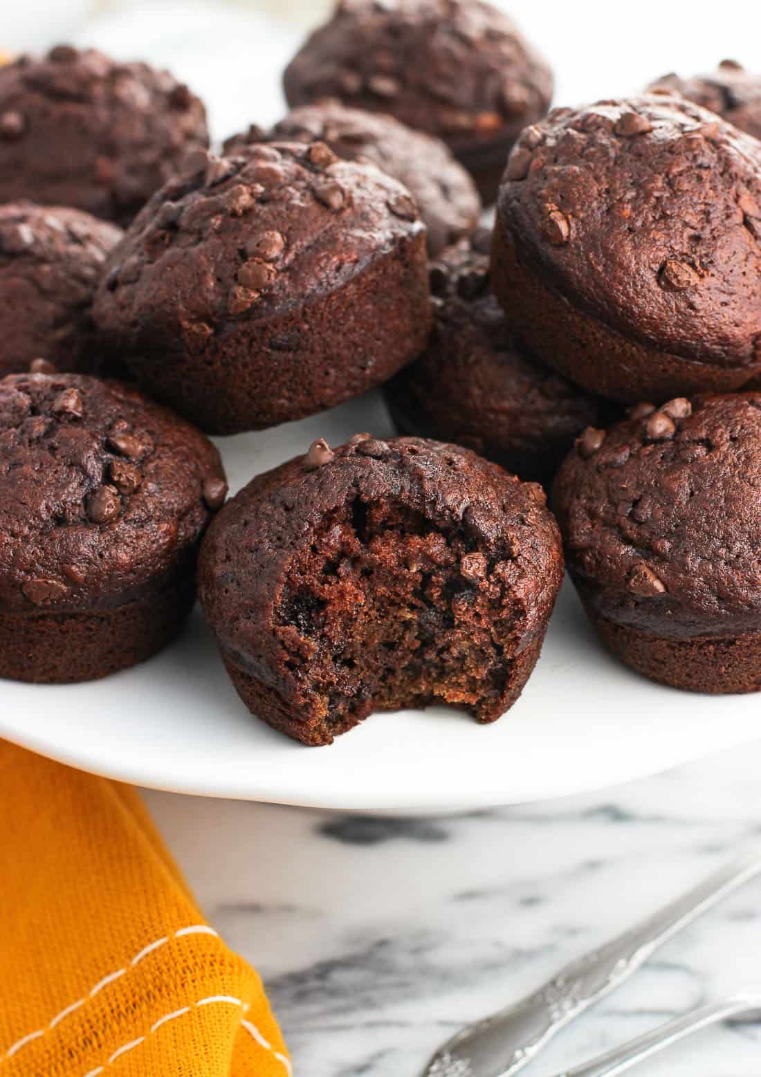 Twelve muffins displayed on a cake stand with a big bite taken out of the front muffin