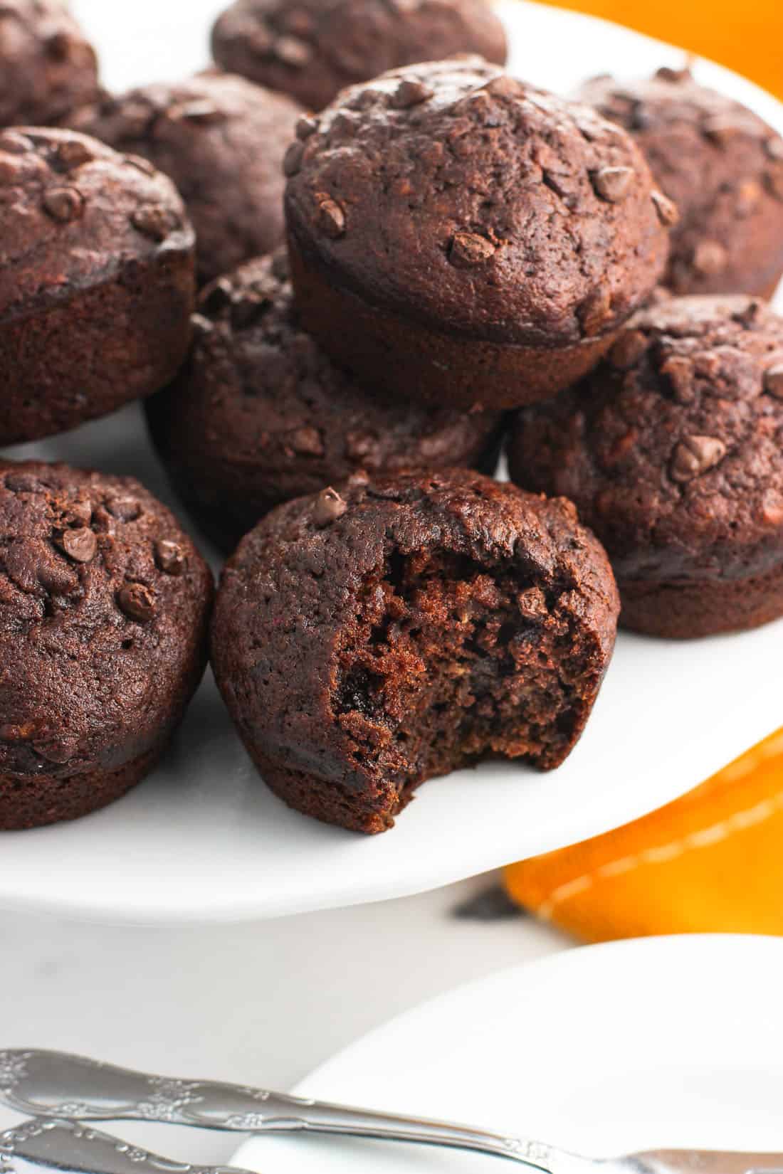 A closer-up image of a bite taken out of a muffin on the cake stand, showing the chocolate chips dotted throughout the muffin