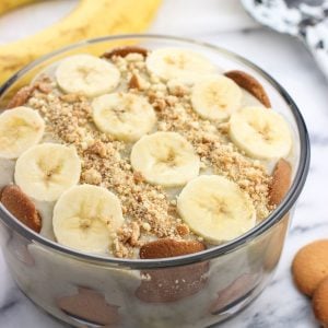 A round glass dish of a layered banana pudding dessert.