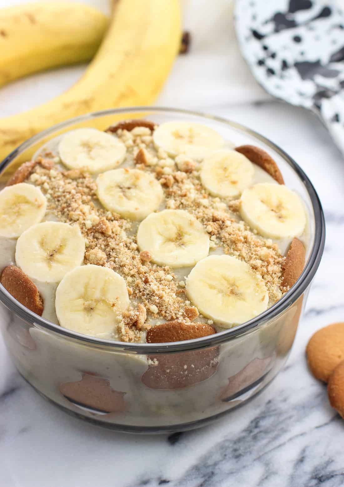 A round glass dish of a layered banana pudding dessert.