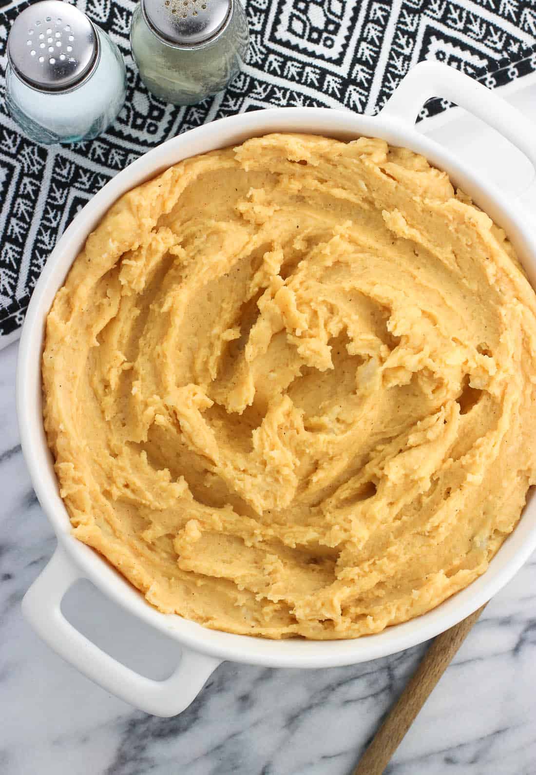 A round dish filled with garlic chipotle mashed potatoes next to salt and pepper shakers.