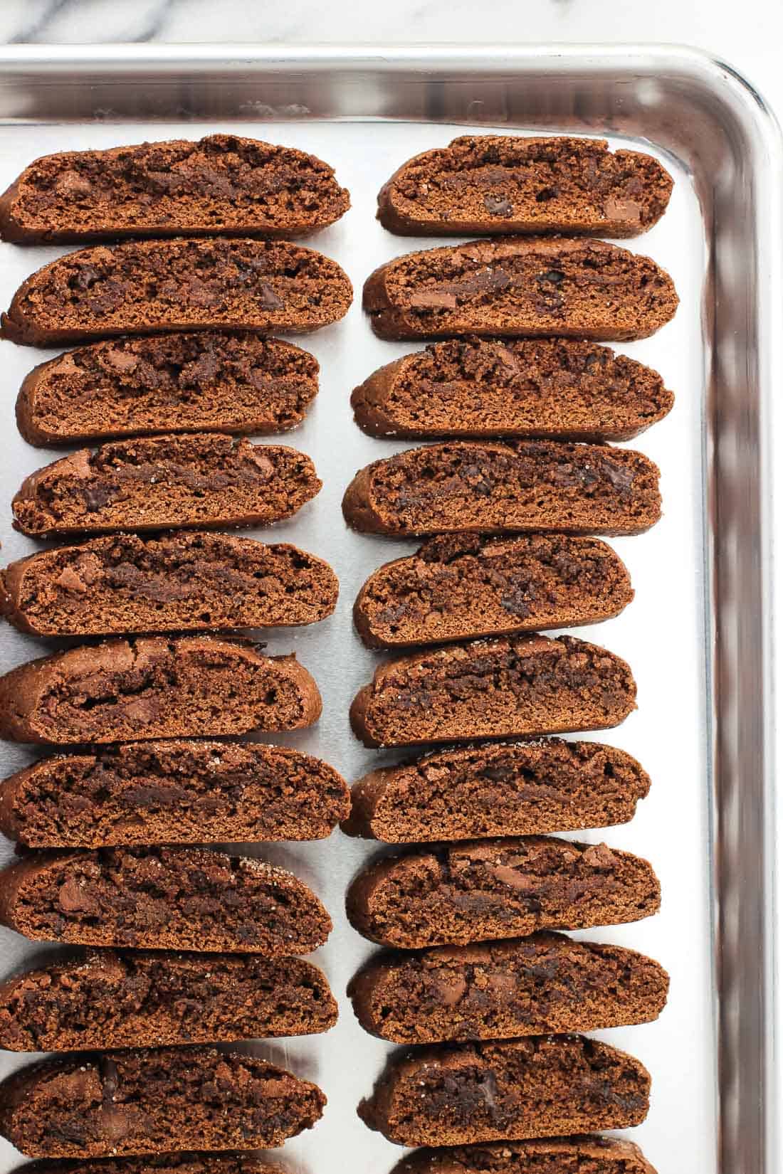 Biscotti lined up on a large parchment-lined baking sheet