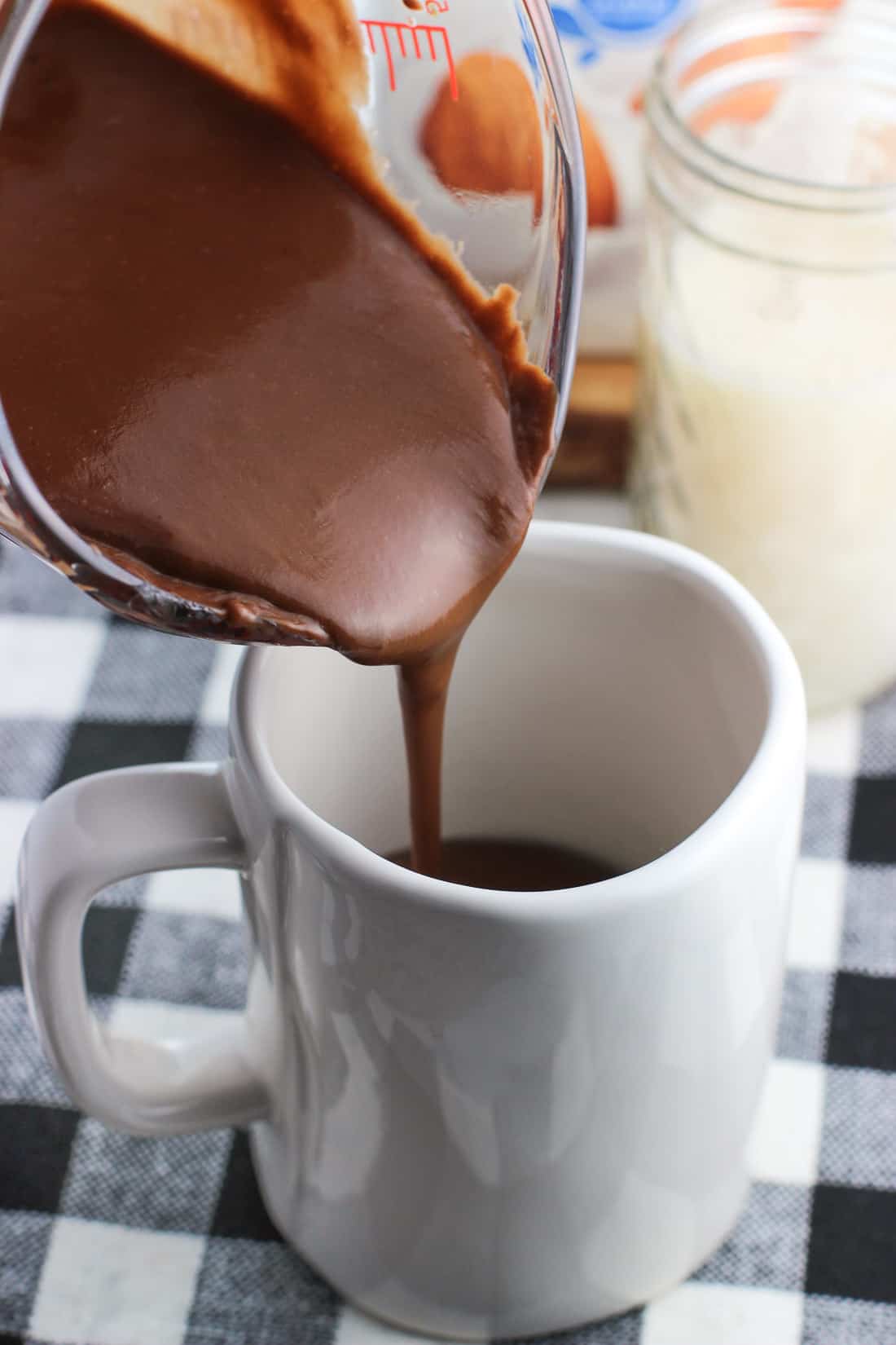 A thick hot chocolate mixture being poured into a ceramic mug.