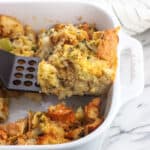 A slice of strata being lifted out of the baking dish by a spatula