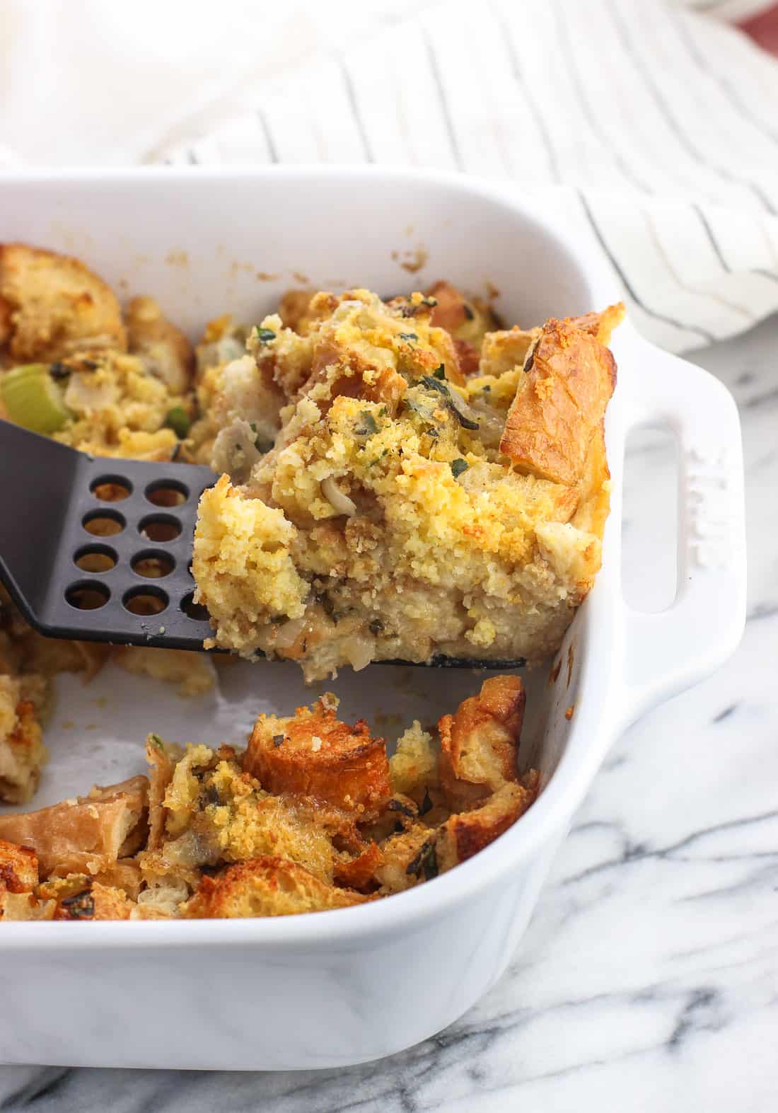 A slice of strata being lifted out of the baking dish by a spatula