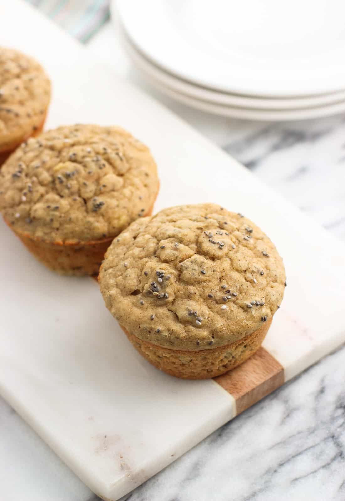 Three banana chia muffins in a line arranged on a white marble board