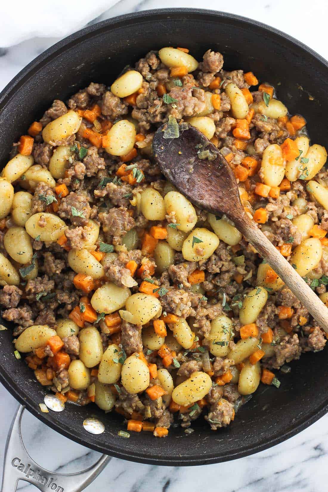 An overhead picture of the gnocchi skillet in a pan with a wooden spoon.