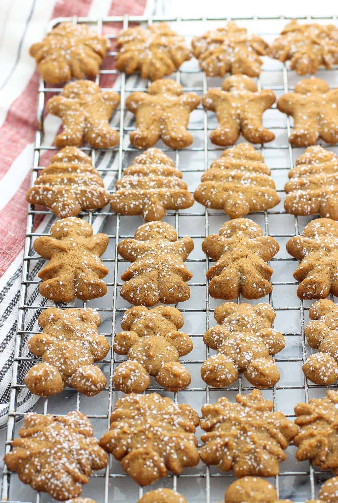 A variety of cookie shapes dusted with powdered sugar on a wire rack.