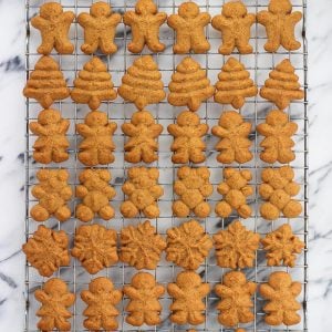 A variety of shaped gingerbread spritz cookies on a wire rack.