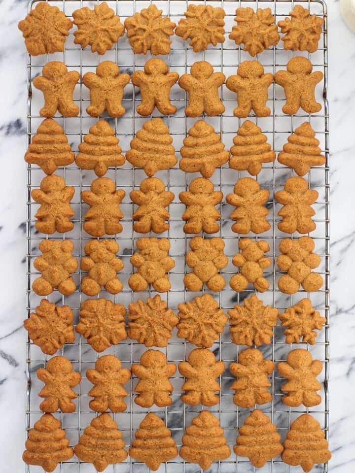 A variety of shaped gingerbread spritz cookies on a wire rack.