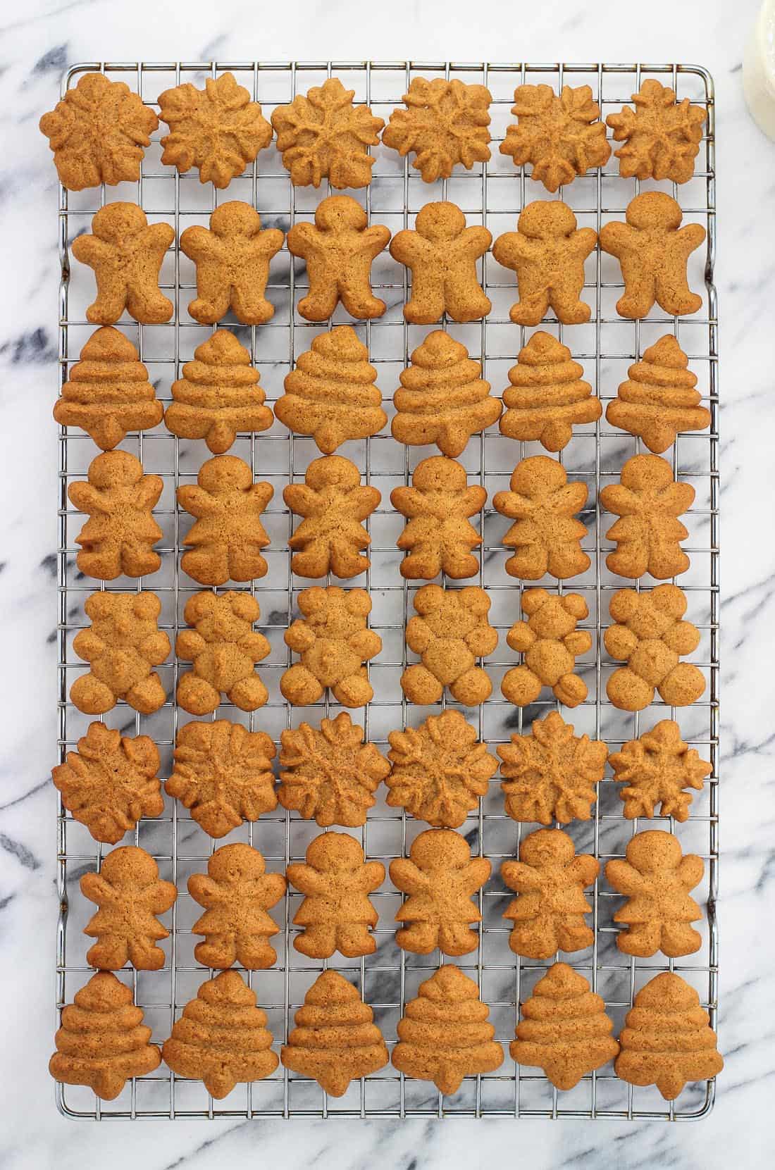 An overhead picture of rows of differently shaped cookies on a wire cooling rack