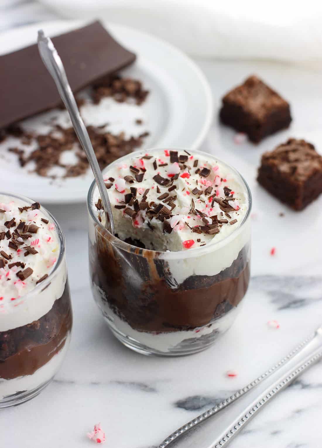 A spoon dug into a small glass of trifle surrounded by recipe ingredients.