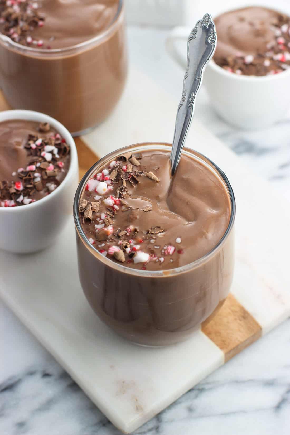 A serving of pudding in a glass with a dessert spoon in the middle of it