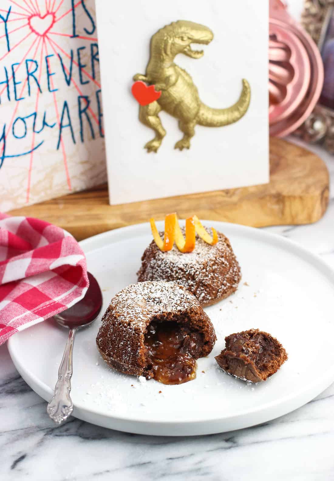 Chocolate orange filling pouring out of one of two lava cakes on a plate.