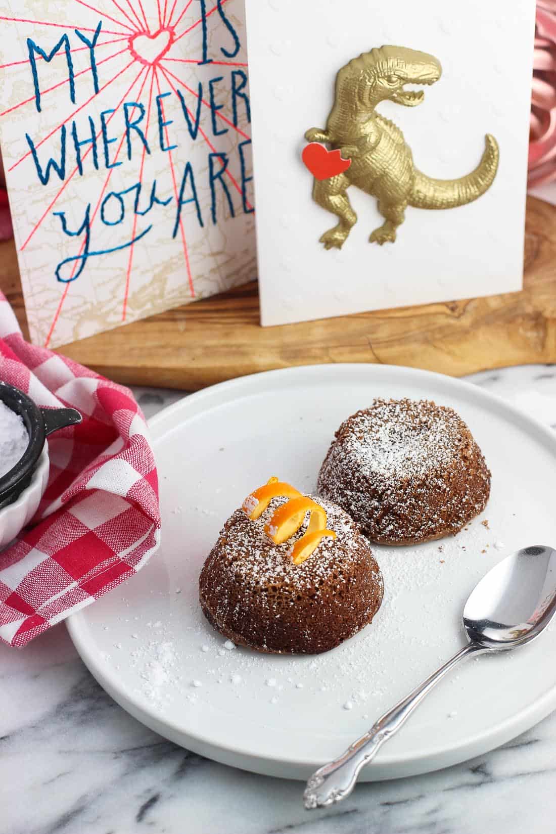 Two lava cakes on a plate with a spoon in front of displayed cards.