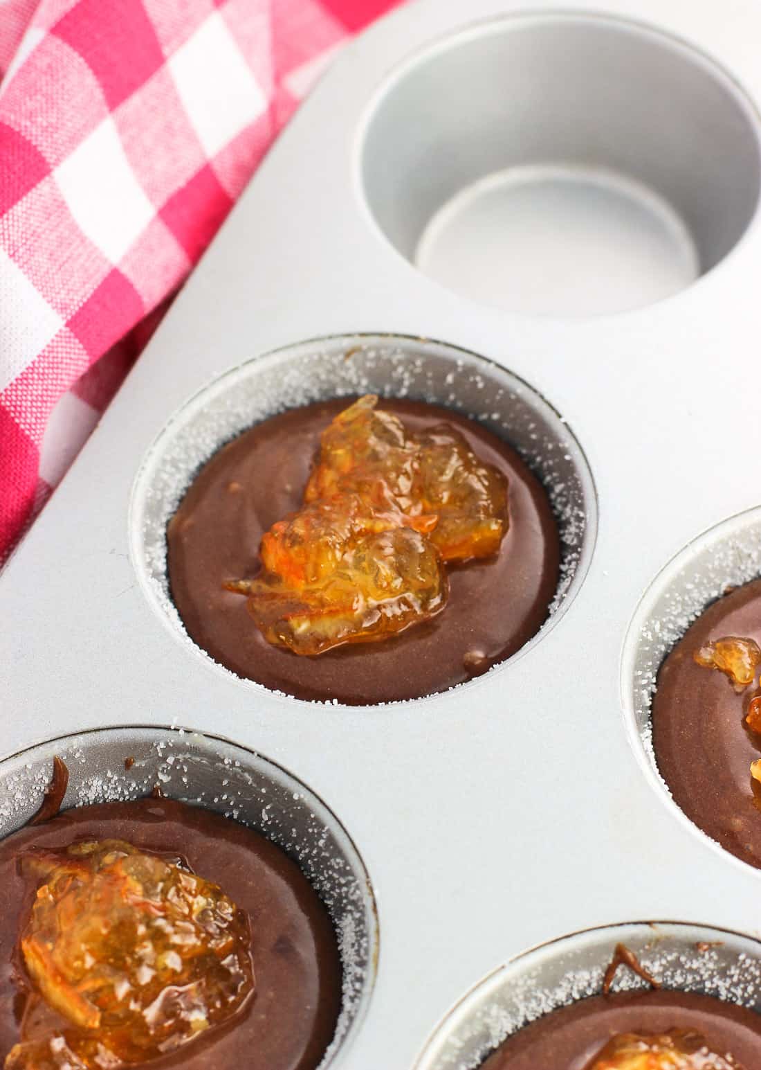 Orange marmalade dollops placed on top of the lava cake batter in the prepared muffin tin