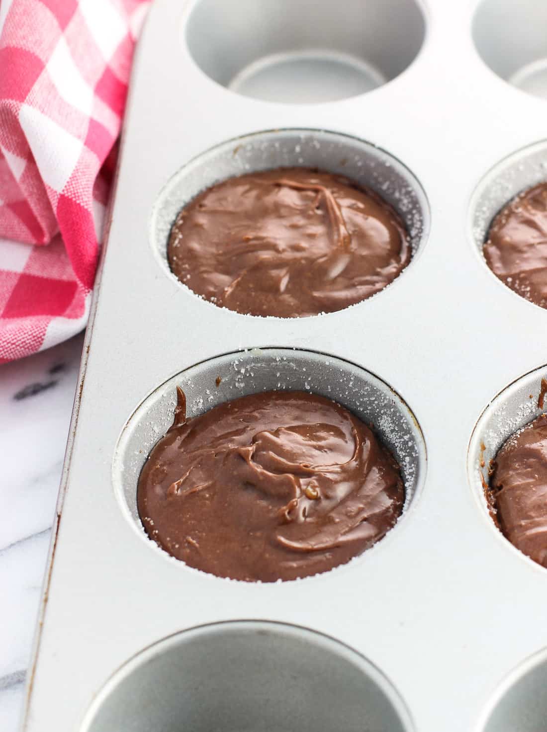 The lava cakes in the metal muffin pan just before going in the oven, after the batter had been scooped to cover the marmalade entirely