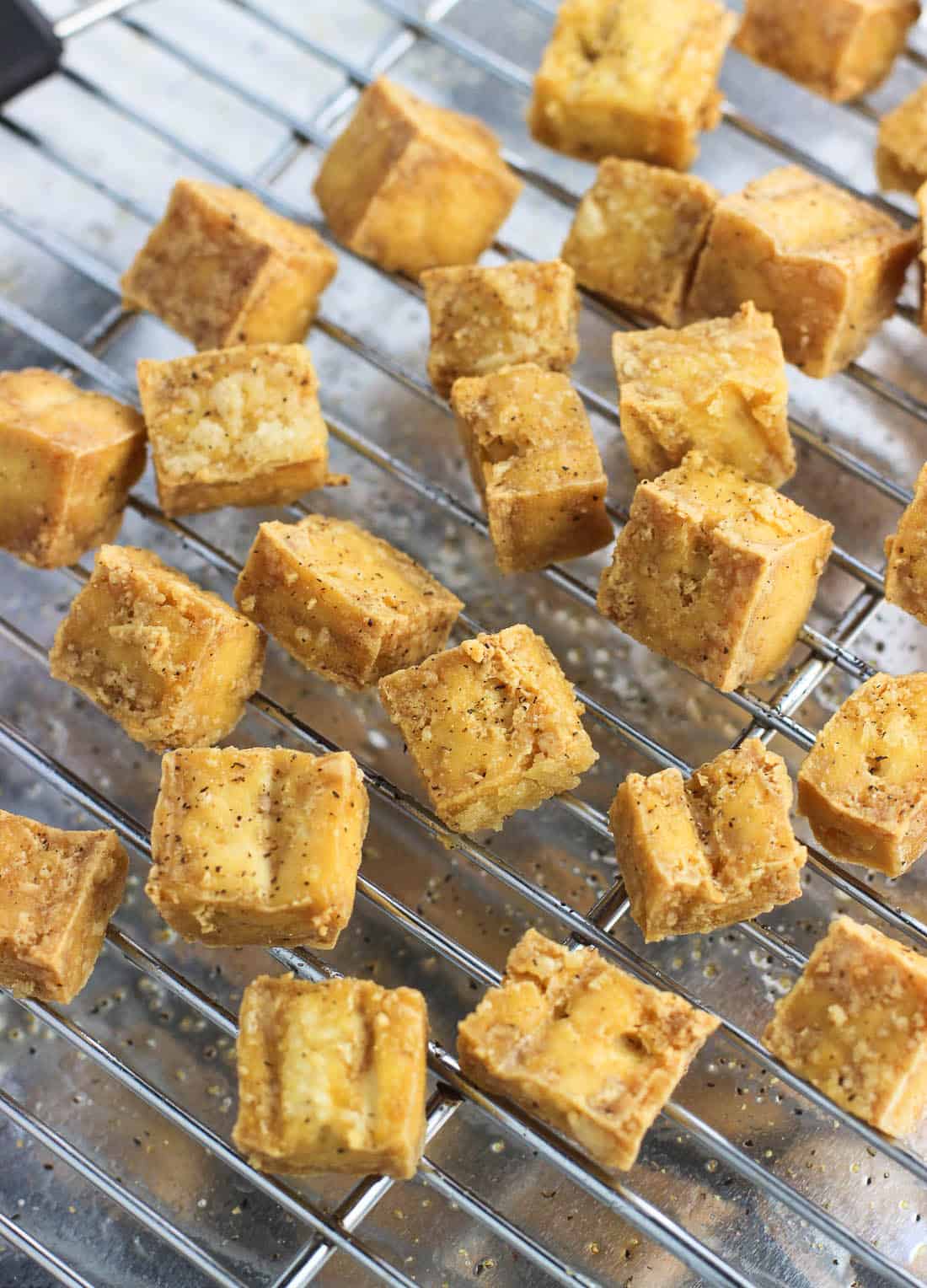 Oven-fried tofu cubes on a wire rack.