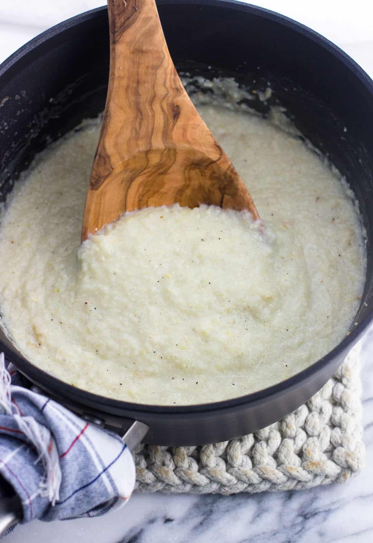 Parmesan grits in a medium saucepan with a wooden spoon