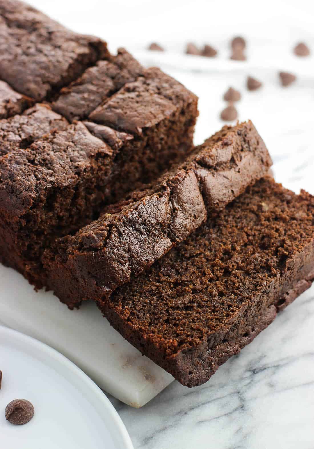 A sliced loaf of chocolate banana bread on a marble board