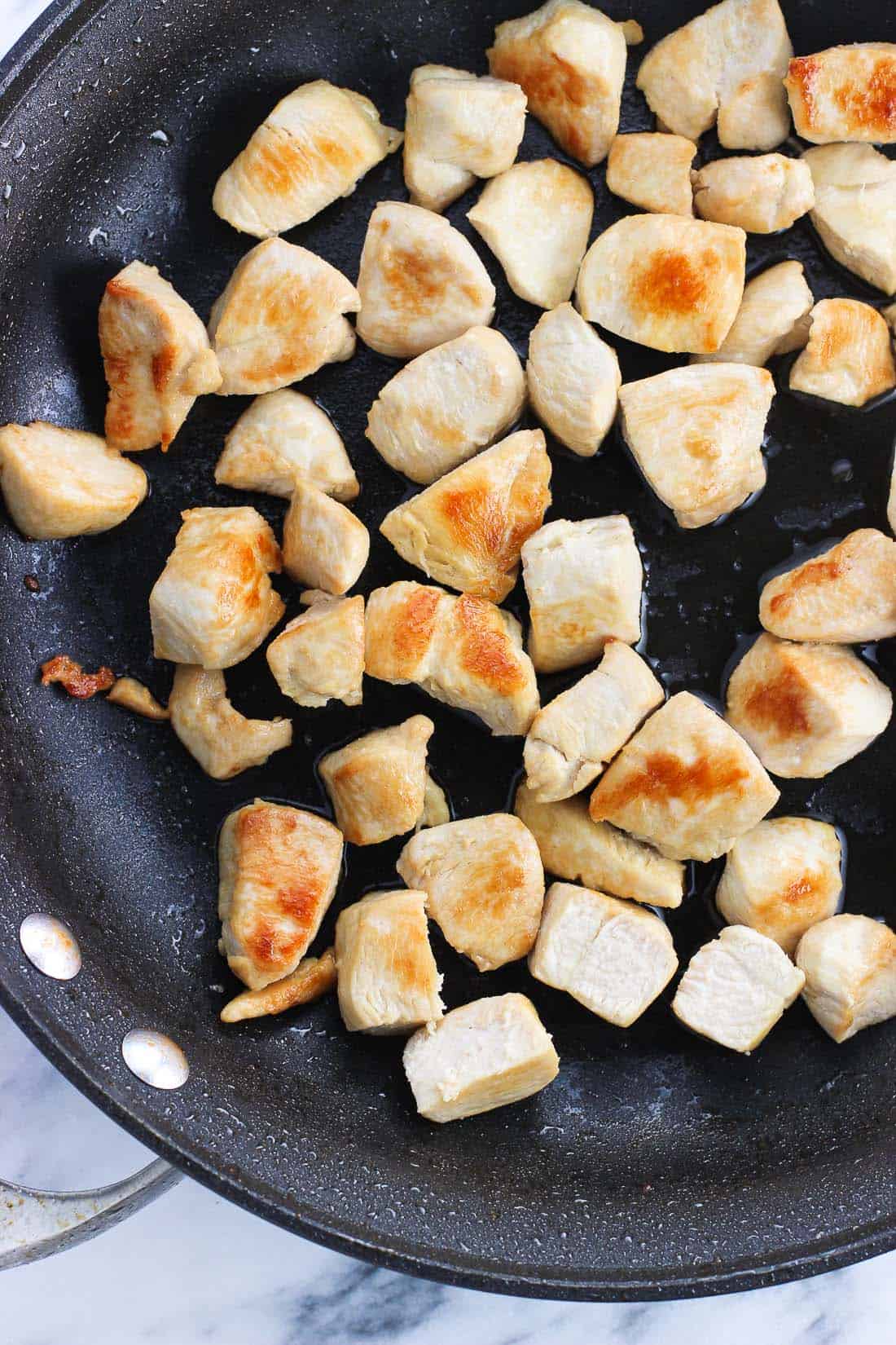 Cooked pieces of plain chicken in a skillet.