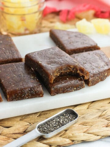 Chia bars stacked on top of one another with a bite taken out of the top bar.