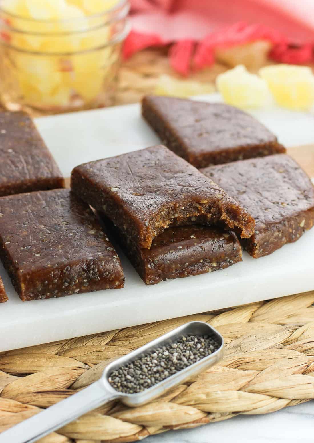 Chia bars stacked on top of one another with a bite taken out of the top bar.