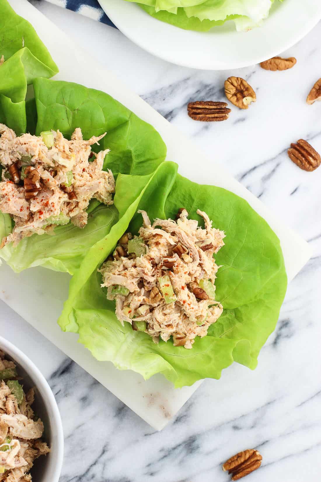 An overhead picture of three cups of lettuce on a rectangular tray filled with chicken salad.