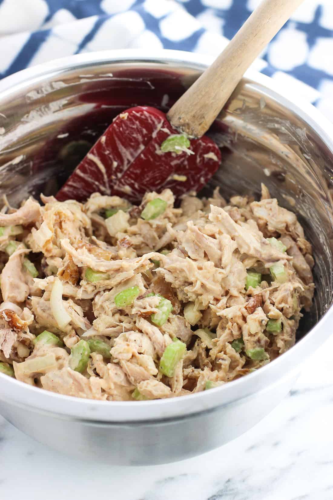 Chicken salad mixed together in a bowl with a spatula.