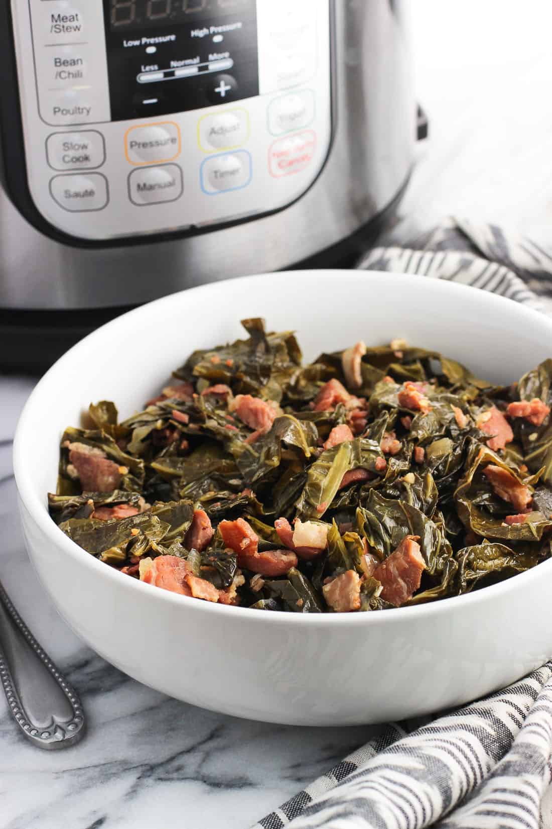 A serving bowl full of Southern collard greens with an Instant Pot in the background.