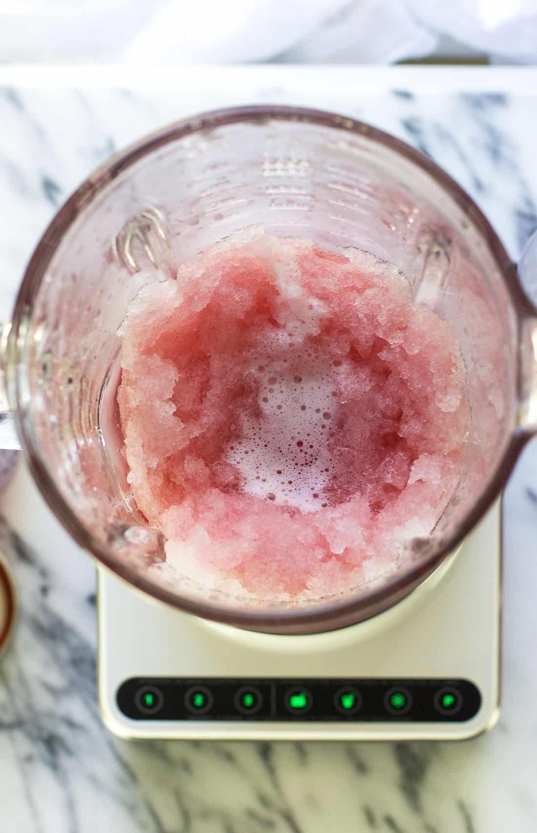 A picture looking into the blender after blending the ice and raspberry iced tea. The ice is very finely crushed