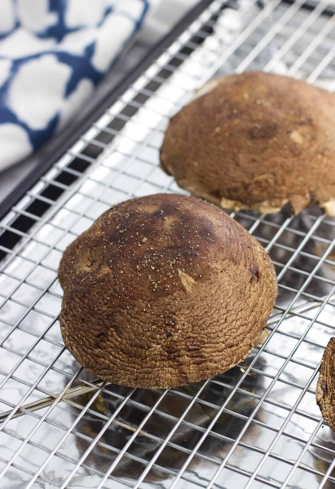 Mushroom caps face-up on a wire rack set over a baking sheet.