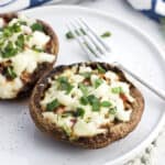 Two open-face portobello mushroom pizzas on a plate with a fork.