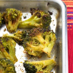 Broccoli florets on a rimmed metal baking sheet roasted and seasoned with Cajun and garlic seasonings