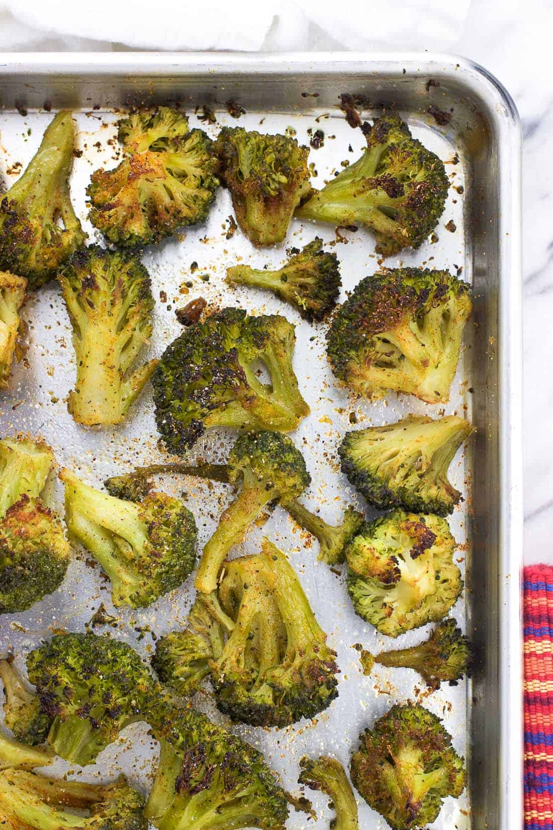 An overhead shot of roasted seasoned broccoli florets on a metal baking sheet