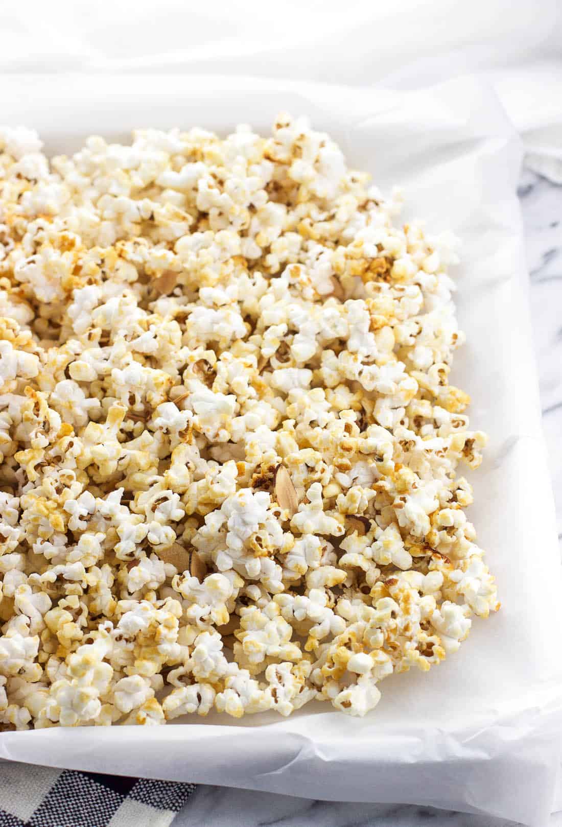 Kettle corn spread out on a parchment paper-lined baking sheet