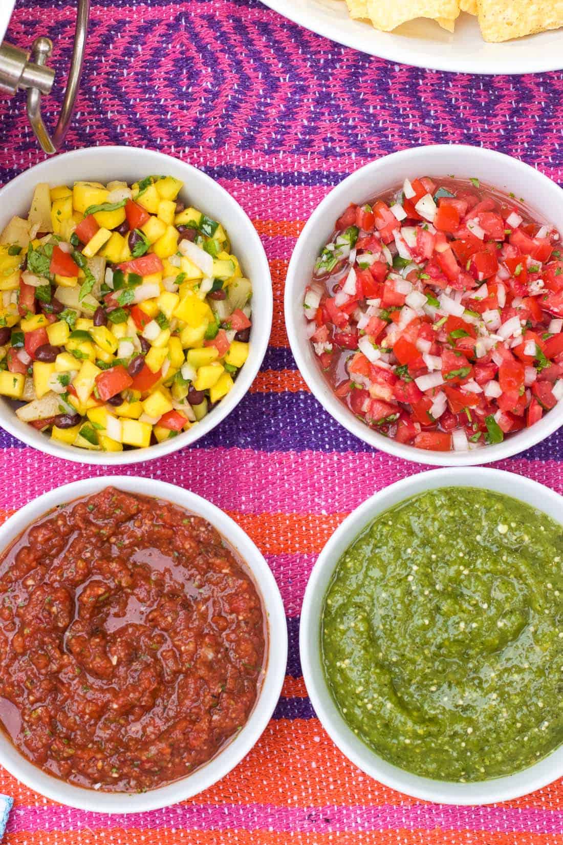 An overhead shot of four bowls of different salsas 