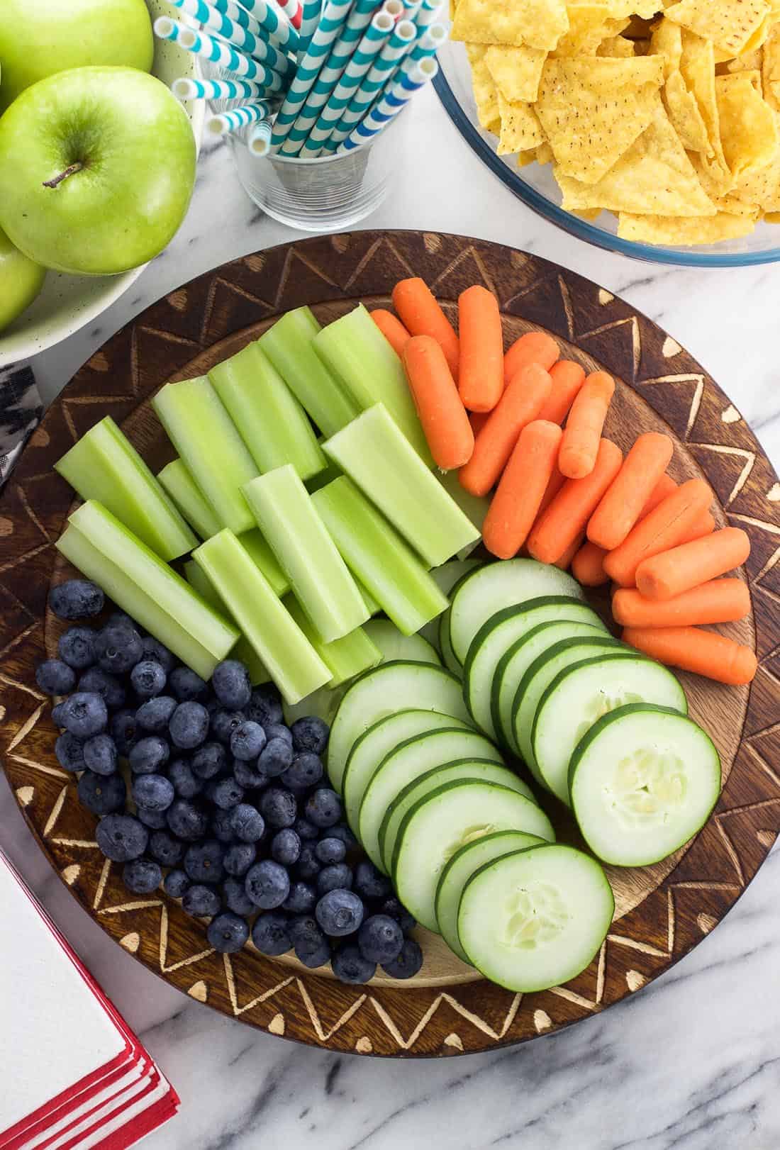 Sliced vegetables and fruit as part of a party spread.