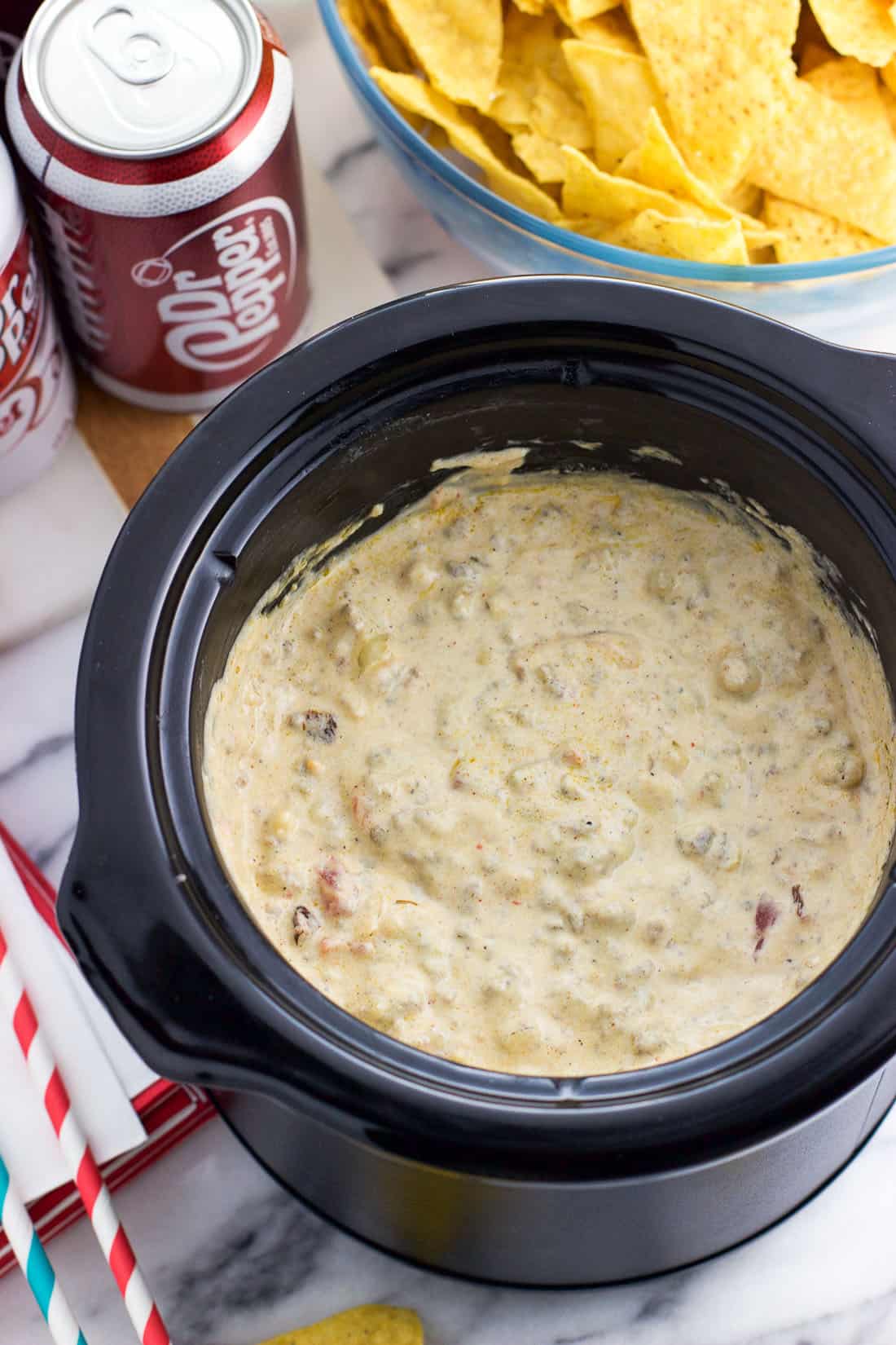 A mini slow cooker filled with cheese dip as part of a party spread.